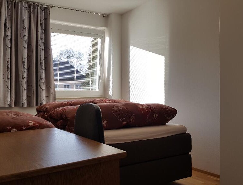 Das Schlafzimmer ist auf einen grünen Innenhof augerichtet und mit einen großen Boxspring Bett, einem großen Schrank und einem Schreibtisch ausgestattet.