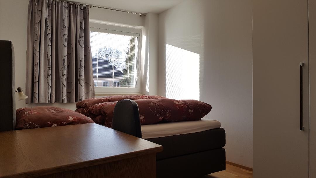 Das Schlafzimmer ist auf einen grünen Innenhof augerichtet und mit einen großen Boxspring Bett, einem großen Schrank und einem Schreibtisch ausgestattet.